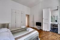 bedroom furnished with queen-size bed, colorful bedspreads, a large dressing area, built-in closets,