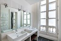 immaculate white en-suite bathroom with double sink and mirror in a 3-bedroom Paris luxury apartment