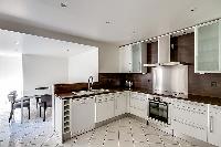 well-equipped kitchen and a dining area with a dining table set for six in a 3-bedroom Paris luxury 