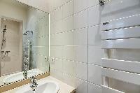 immaculate white en-suite bathrooms with sink and detachable shower head in a 3-bedroom Paris luxury