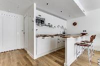well-equipped space-efficient kitchen with breakfast bar and stools in a 1-bedroom paris luxury apar