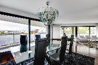 elegant dining area with a glass table and six black chairs in a 2-bedroom Paris luxury apartment