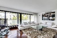 spacious living area furnished with two white couches, an elegant fuzzy rug, and a center table, and