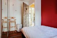 cozy bedroom with floor to ceiling mirrors, a hamper, and a queen-size bed in a 1-bedroom Paris luxu