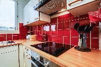 warm and inviting red kitchen in a 1-bedroom Paris luxury apartment