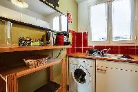 warm and inviting kitchen with a combo washer and dryer in a 1-bedroom Paris luxury apartment