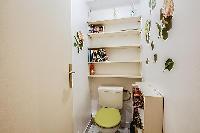 wash closet with a toilet and bookshelves in a 1-bedroom Paris luxury apartment