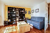 spacious living area with large shelves filled with books, a wooden center table, and a double sofa 