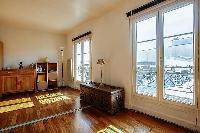 spacious living area with large shelves filled with books, a wooden center table, and a double sofa 