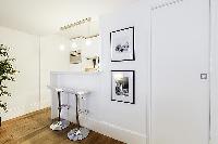 sleek and white breakfast bar and stools in a 1-bedroom Paris luxury apartment