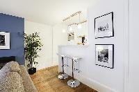 sleek and white breakfast bar and stools in a 1-bedroom Paris luxury apartment