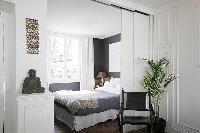 cozy and classy bedroom with two bedside tables, a lamp, and a queen-size bed in a 1-bedroom Paris l