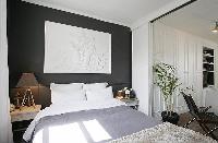 cozy and classy bedroom with two bedside tables, a lamp, and a queen-size bed in a 1-bedroom Paris l