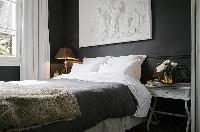 cozy and classy bedroom with two bedside tables, a lamp, and a queen-size bed in a 1-bedroom Paris l