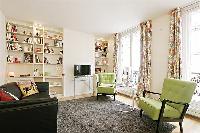 bright and cozy living area with two armchairs, well-stocked bookshelves, a sofa bed, and a flat-scr