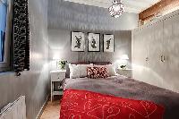 bedroom with built-in cabinets, two bedside tables with lamps, and a double bed 1-bedroom Paris luxu