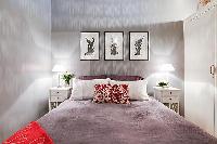 bedroom with built-in cabinets, two bedside tables with lamps, and a double bed 1-bedroom Paris luxu