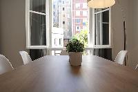 wooden dining table and white chairs for six, floor lamp, and bright window overlooking the street i