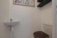 A water closet with toilet and sink in a 2-bedroom Paris luxury apartment