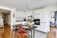 modern dining area with dining table and chairs in grey and apricot hues in a 2-bedroom Paris luxury