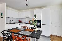 modern kitchen and dining area with dining table and chairs in grey and apricot hues in a 2-bedroom 