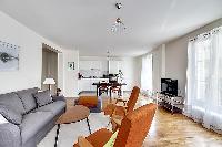 minimalist living room with a grey sofa bed, two apricot armchairs, a center table, and a cabinet wi