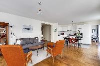 minimalist living room with a grey sofa bed, two apricot armchairs, a center table, and a cabinet wi