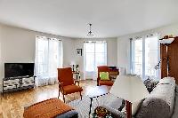 minimalist living room with a grey sofa bed, two apricot armchairs, a center table, and a cabinet wi