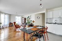 modern kitchen and dining area with dining table and chairs in grey and apricot hues in a 2-bedroom 