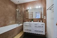 bathroom fully-equipped with double sinks, a bathroom cabinet, a mirror, and a bathtub with a detach