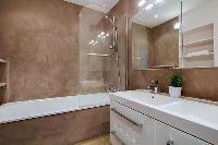 bathroom fully-equipped with double sinks, a bathroom cabinet, a mirror, and a bathtub with a detach