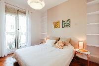 chic master bedroom is furnished with a queen-size bed, two bedside tables, built-in shelves, and Fr