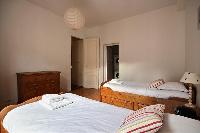 A combo washer and dryer, iron, and ironing board in a 2-bedroom Paris luxury apartment