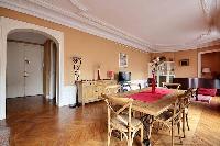 classic long open plan living area with dining set for six in a 2-bedroom Paris luxury apartment