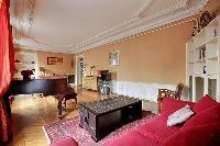 elegant and rustic living area with a big red sofa, a center table, shelves, a television, and a gra