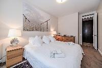 fourth bedroom furnished with a queen-size bed, two bedside tables with lamps, a nightstand, and Fre