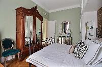 classic bedroom equipped with a queen-size bed, a large wardrobe, built-in cabinets, and a nightstan