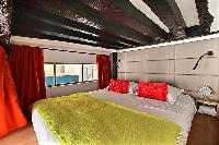 second bedroom with a queen-size bed, and a bedside table with a mirror in a 2-bedroom Paris luxury 