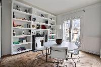 round table with 4 white chairs, shelves, and ornamental fireplace in a Paris luxury apartment