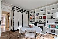 round table with 4 white chairs, shelves, and ornamental fireplace in a Paris luxury apartment