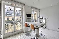 white breakfast bar and stools, TV, and tall windows in Paris luxury apartment