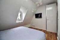 second bedroom with a queen-size bed, two bedside tables with lamps, and a built-in closet with a mi