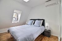 second bedroom with a queen-size bed, two bedside tables with lamps, and a built-in closet with a mi