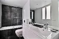 sleek black and white bathroom fully-equipped with a toilet, double sinks, a bathroom cabinet, a mir