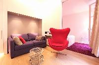 open plan living area with a purple sofa bed, an a red large armchair  in a 2-bedroom Paris luxury a