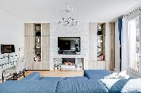 spacious living space with an L-shaped muted blue sofa, built-in shelves with decorative pieces, a t