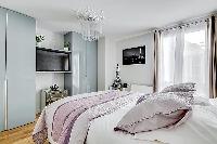 chic bedroom with a queen-size bed, built-in shelves, side tables, and a television in a 2-bedroom p