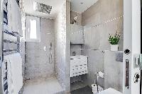 cozy bathroom in slate grey with a toilet, a sink, bathroom drawers, a mirror, a shower area with a 