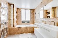cozy bathroom in brown and white motif with a toilet, double sinks, bathroom shelves, a mirror, a ba