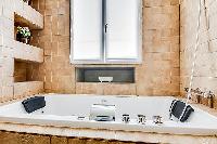 cozy bathroom in brown and white motif with a toilet, double sinks, bathroom shelves, a mirror, a ba